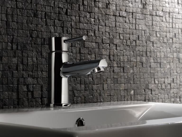 A Roper Rhodes Storm chrome basin mixer on a white basin against a dark textured mosaic wall