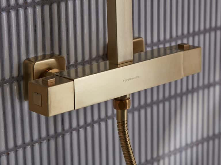A Roper Rhodes Recite thermostatic bar valve in brushed brass on a stacked tile shower wall