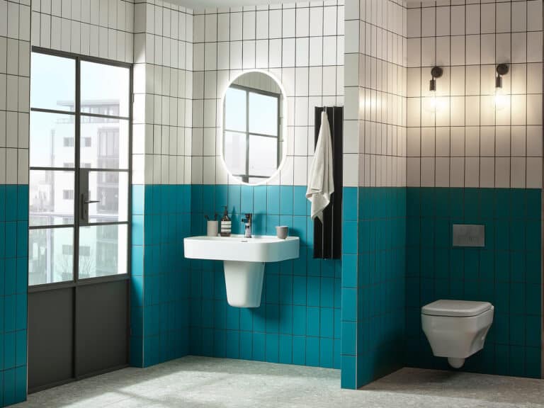 A Roper Rhodes Accent wall hung WC and basin against teal tiles in a room with a crittall window