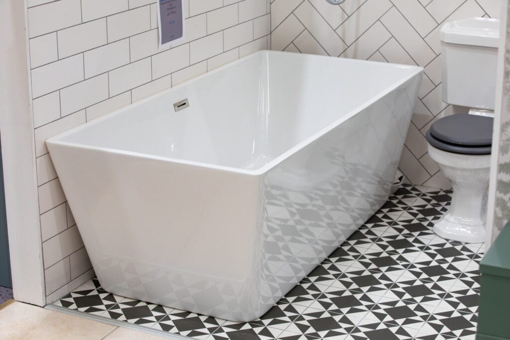A rectangular freestanding bath on a black and white patterned floor