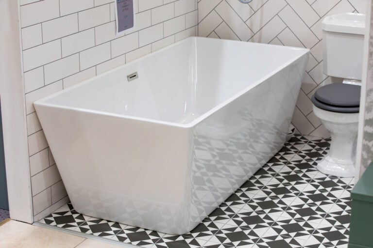 A rectangular freestanding bath on a black and white patterned floor