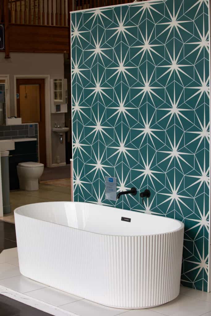 A fluted freestanding bath against a teal star patterned wall, seen from the room