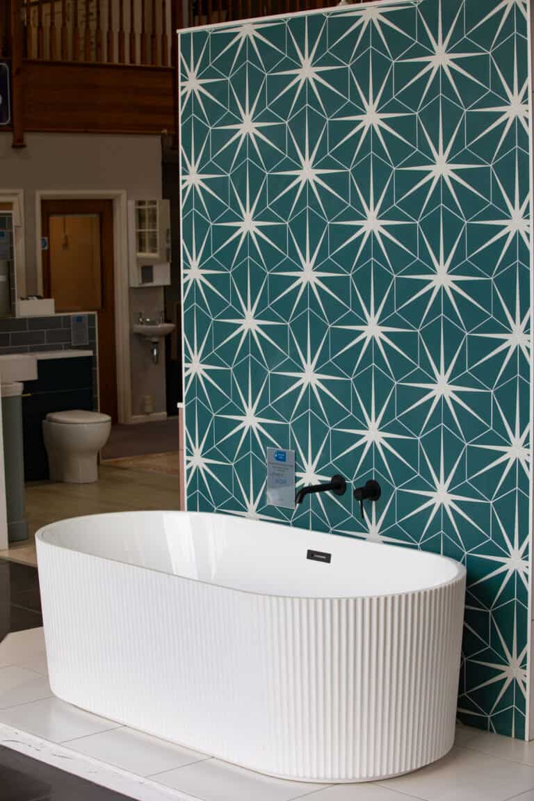 A fluted freestanding bath against a teal star patterned wall, seen from the room