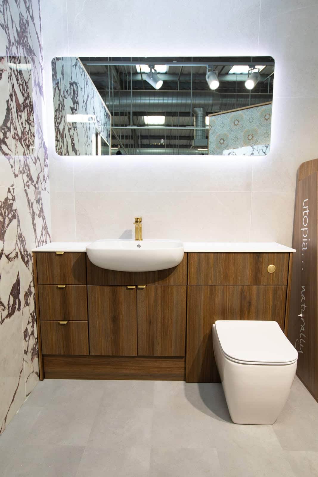 A walnut vanity unit and WC with a long illuminated mirror