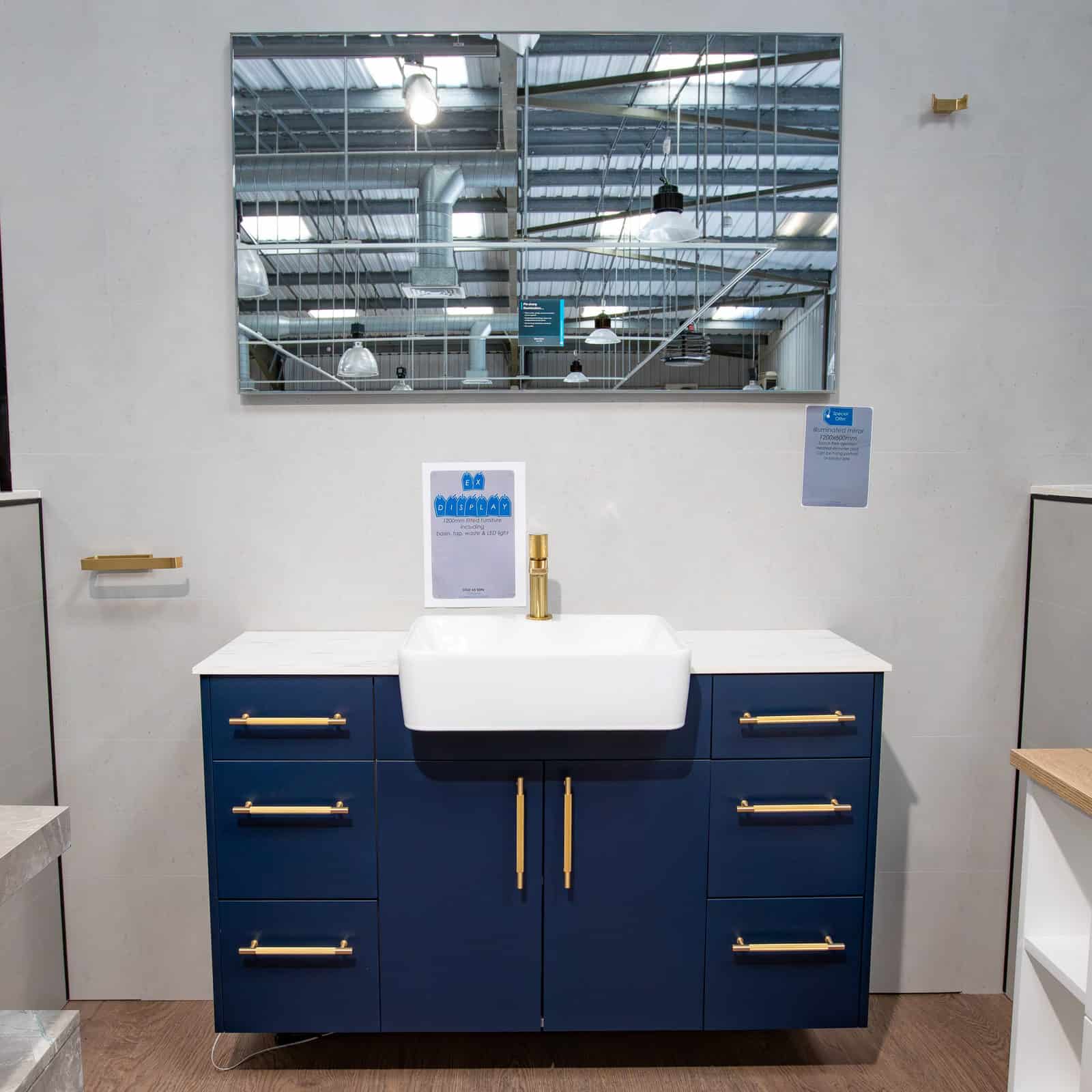 A navy vanity unit with brass handles and a wide mirror above