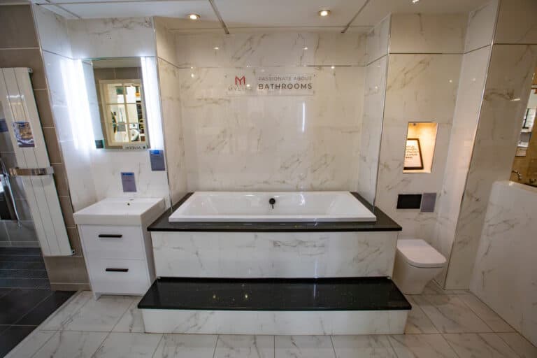 An inset bath set into a marble tiled surround