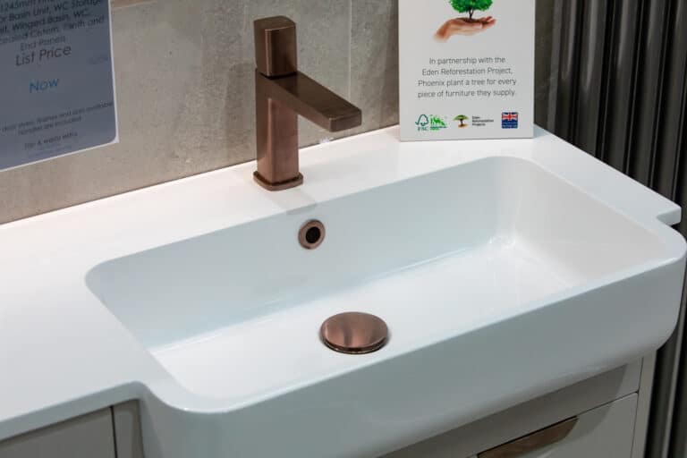 A white basin with a brushed copper tap
