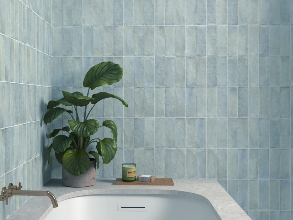 Craven Dunnill Sabbia Storm Blue square wall tiles above a bath with a brass wall-mounted filler