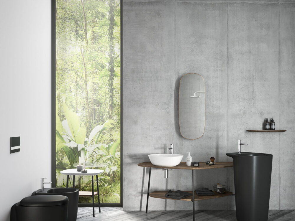 VitrA Plural black pedestal washbasins in a concrete-walled bathroom with a garden view