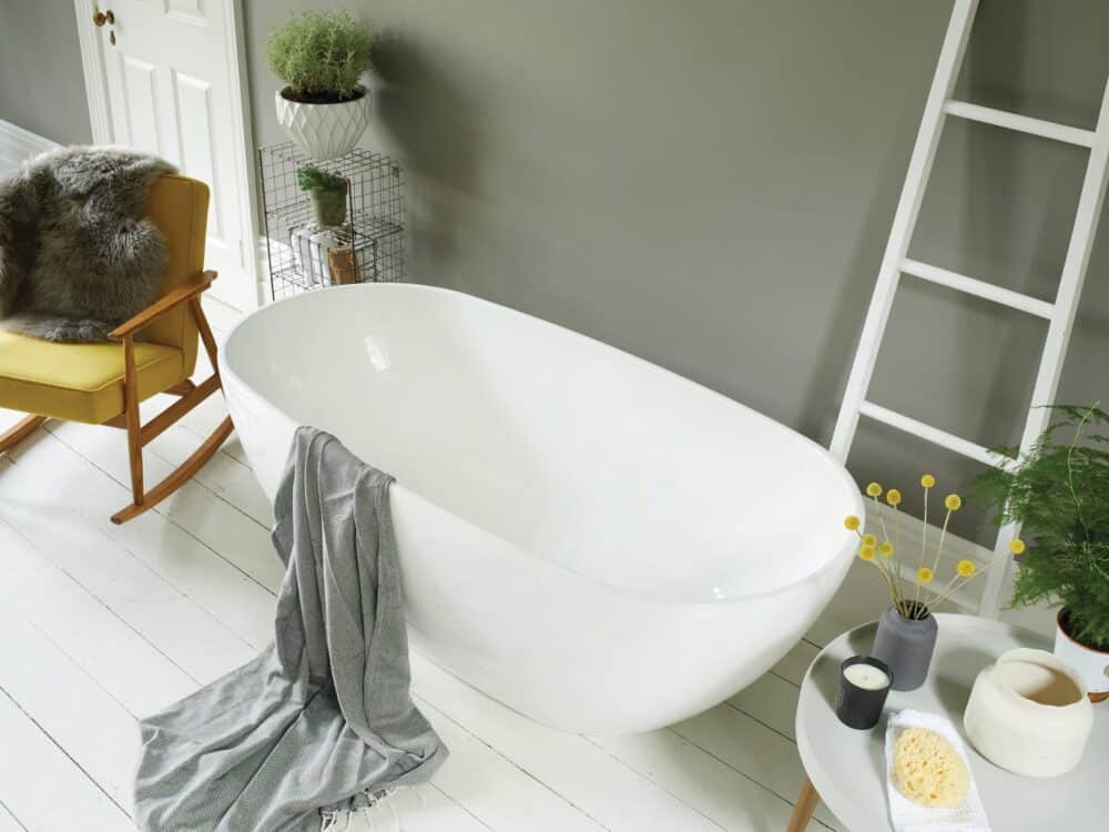 Waters Brook freestanding bath against a green wall with a rocking chair and ladder shelf